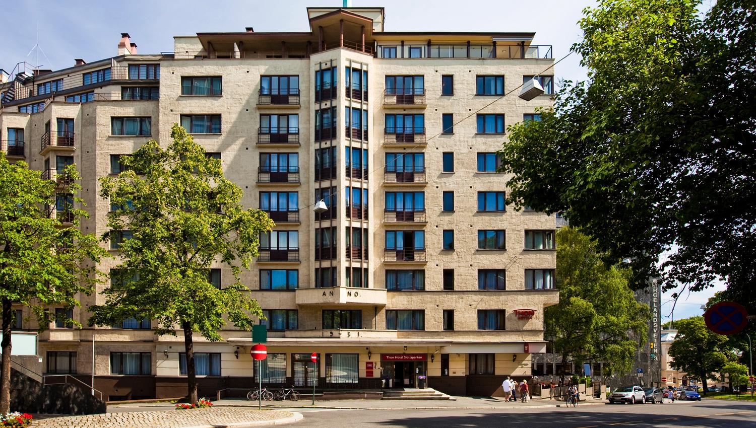 Street view, Thon Hotel Slottsparken in Oslo. Green trees, blue sky. Photo.