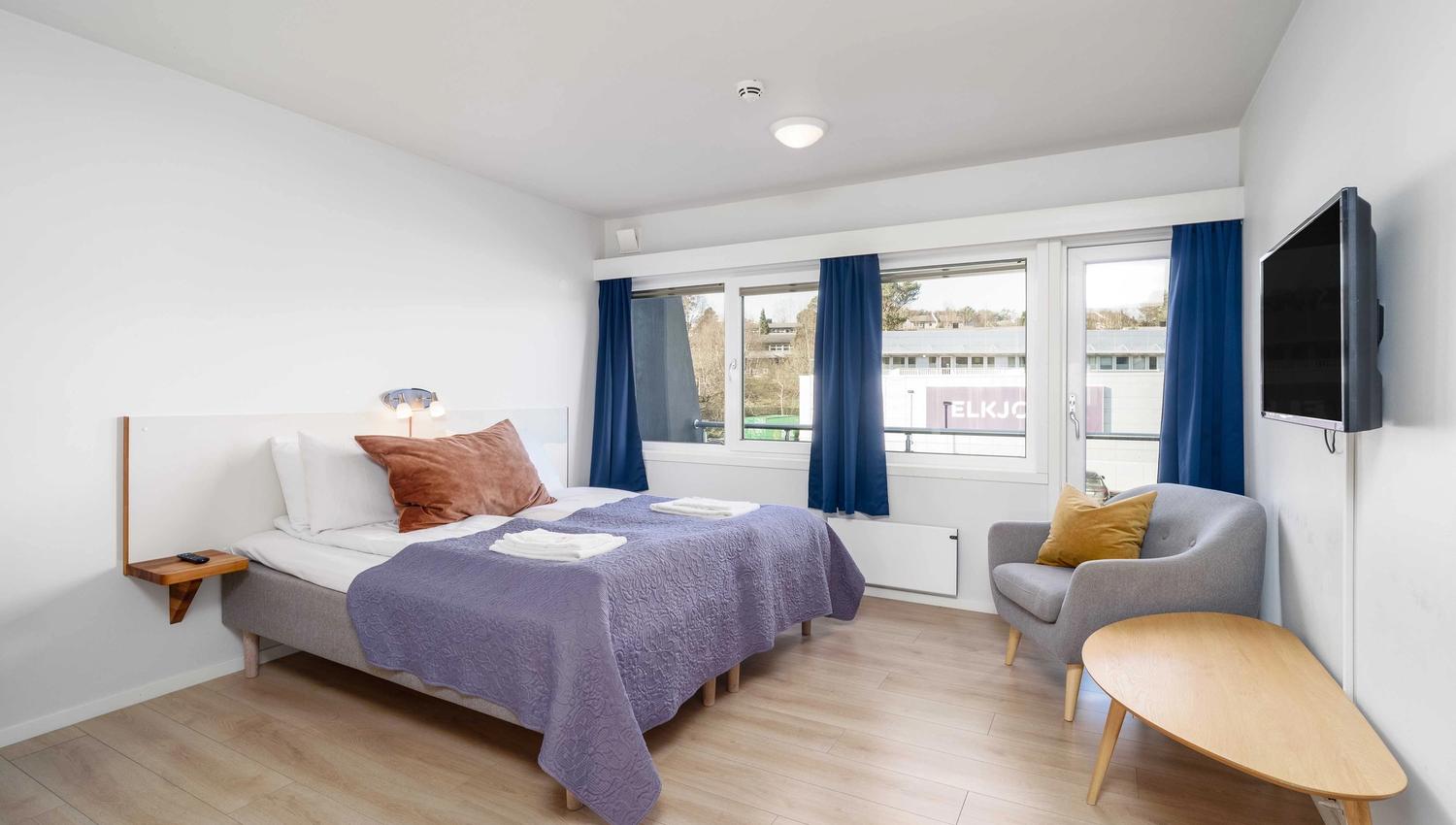 Bright and inviting hotel room at Husnes Sentrum Hotel with large windows and a calm atmosphere.