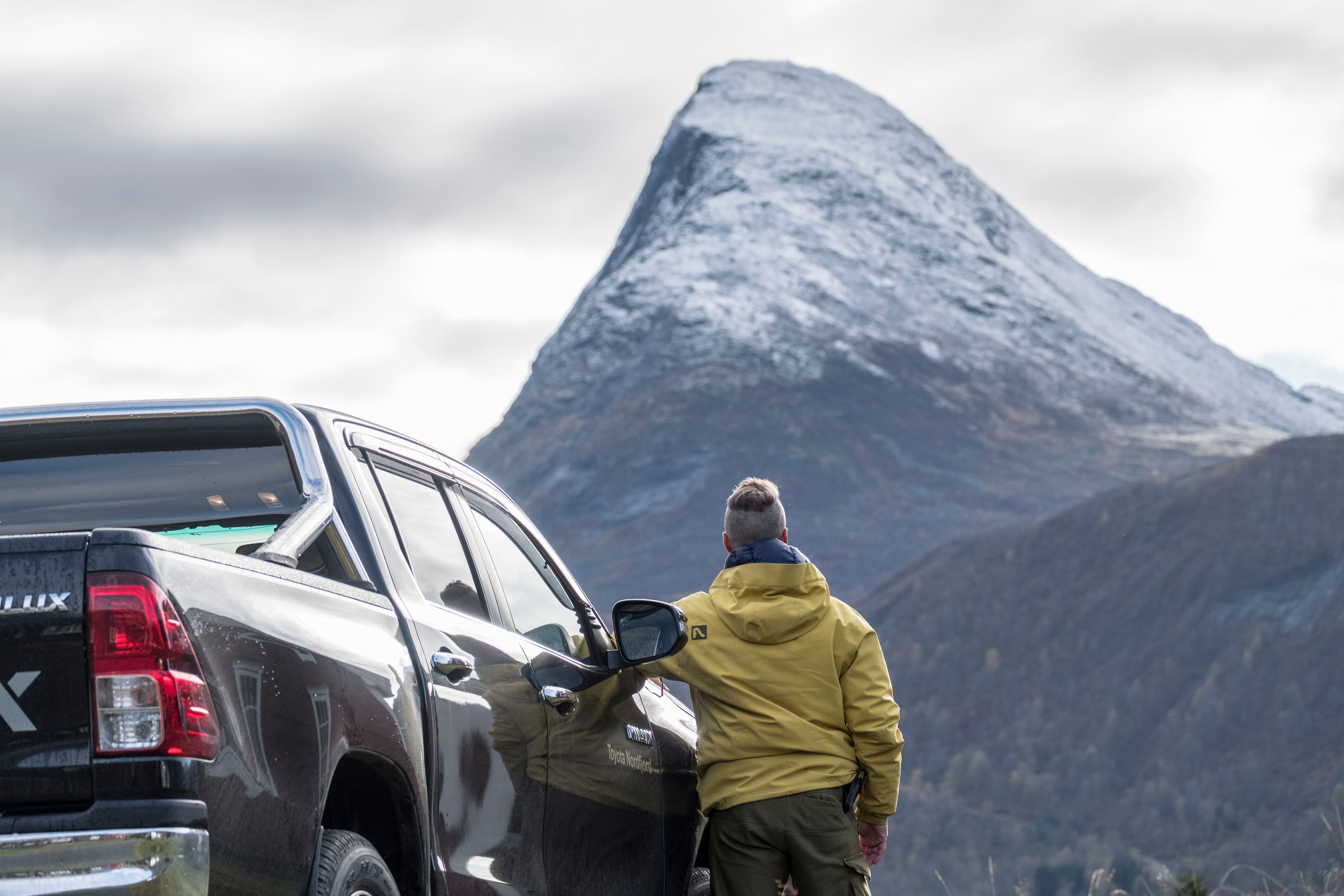 Traveler by Pickup Facing Mount Hornindalsrokken. in Hornindal in Volda.