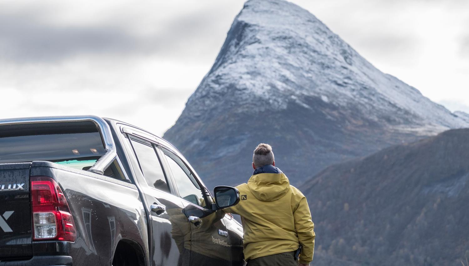 Traveler by Pickup Facing Mount Hornindalsrokken. in Hornindal in Volda.