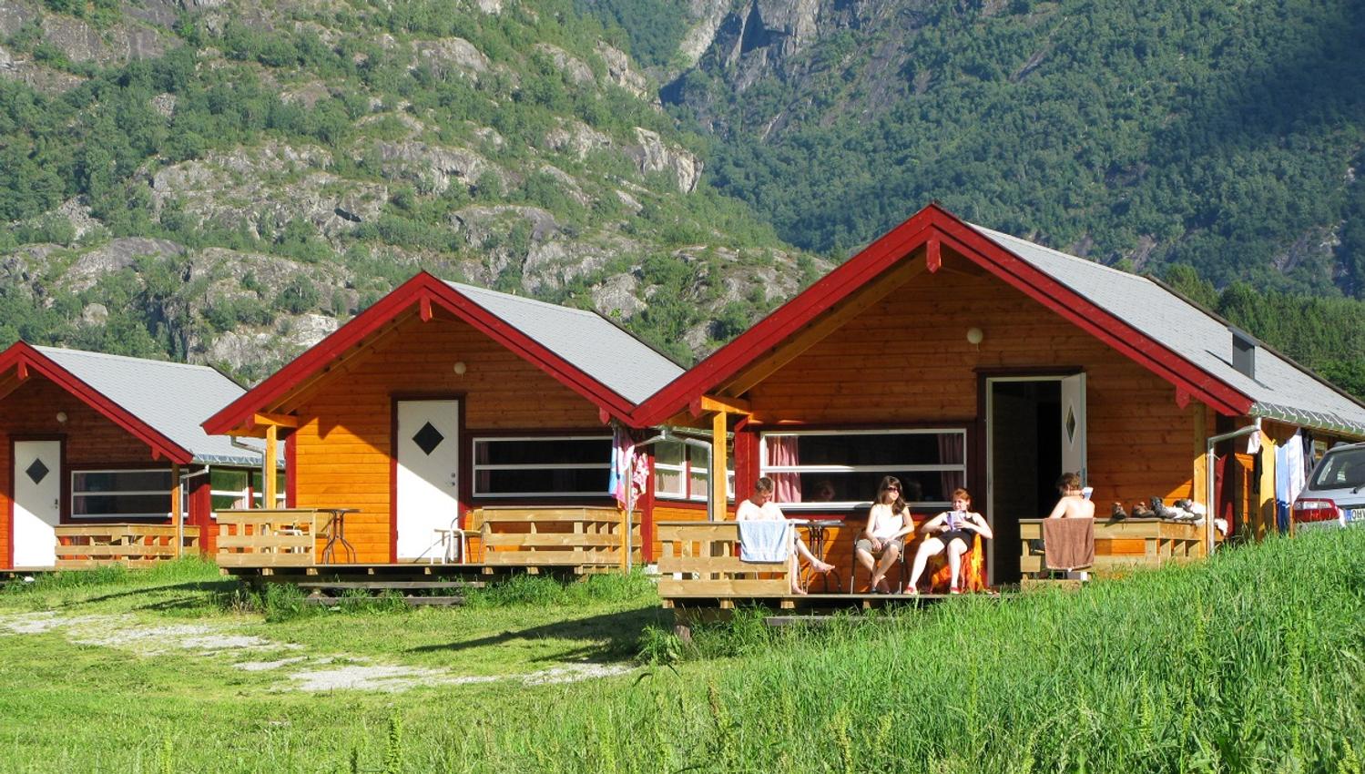 Three of the cabins at the campground, with people lounging on one of the patios.