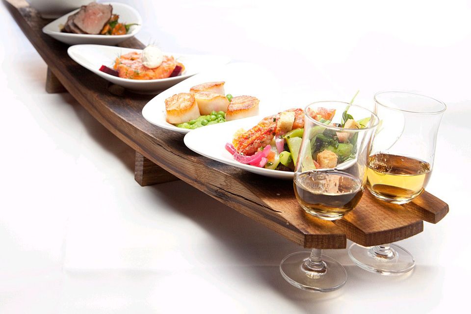 Detail photo of various small dishes on a tray and two wine glasses.