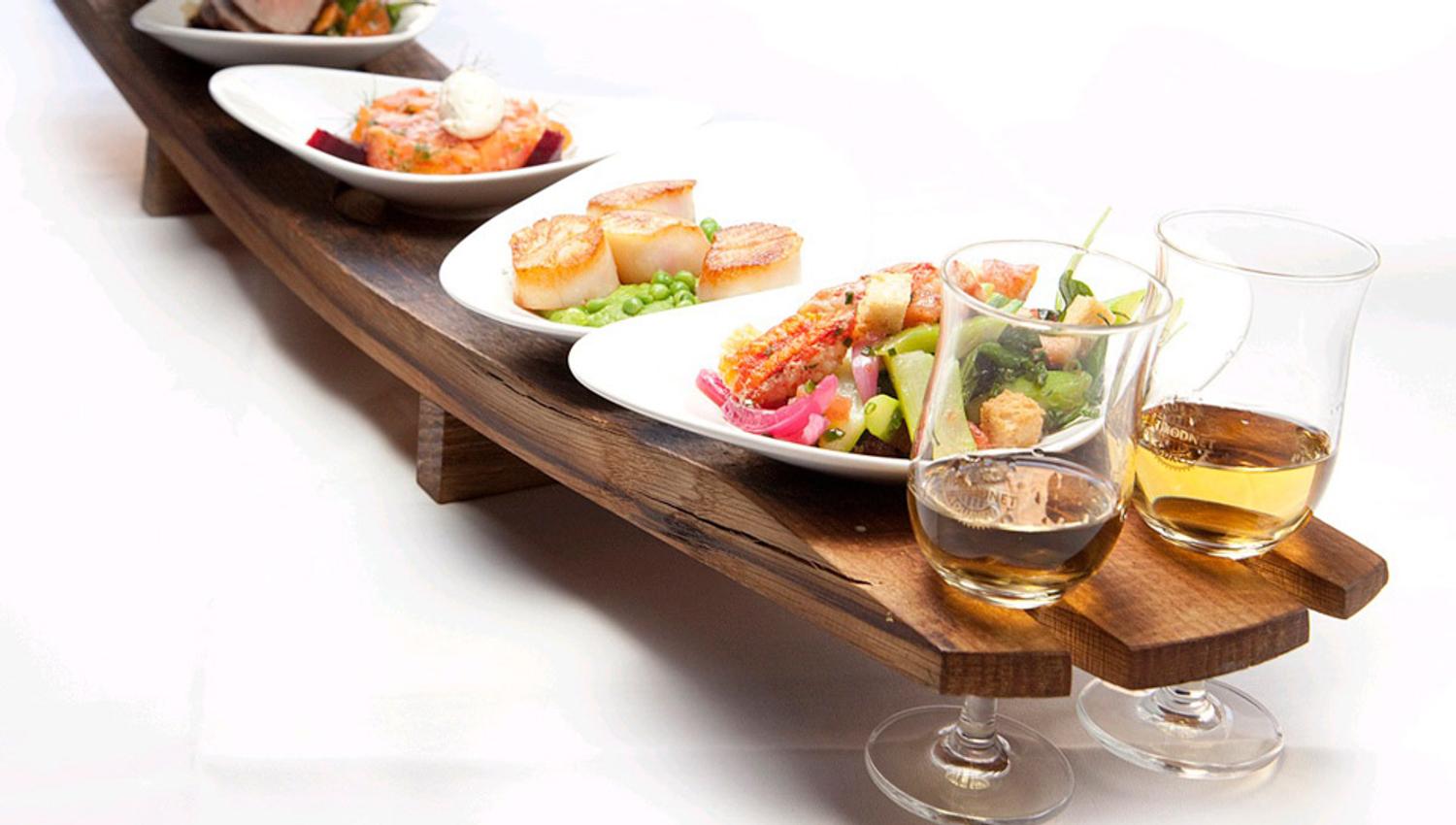 Detail photo of various small dishes on a tray and two wine glasses.