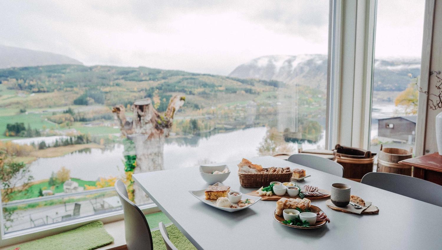 A table filled with local food from Hardanger, overlooking a panoramic fjord landscape.