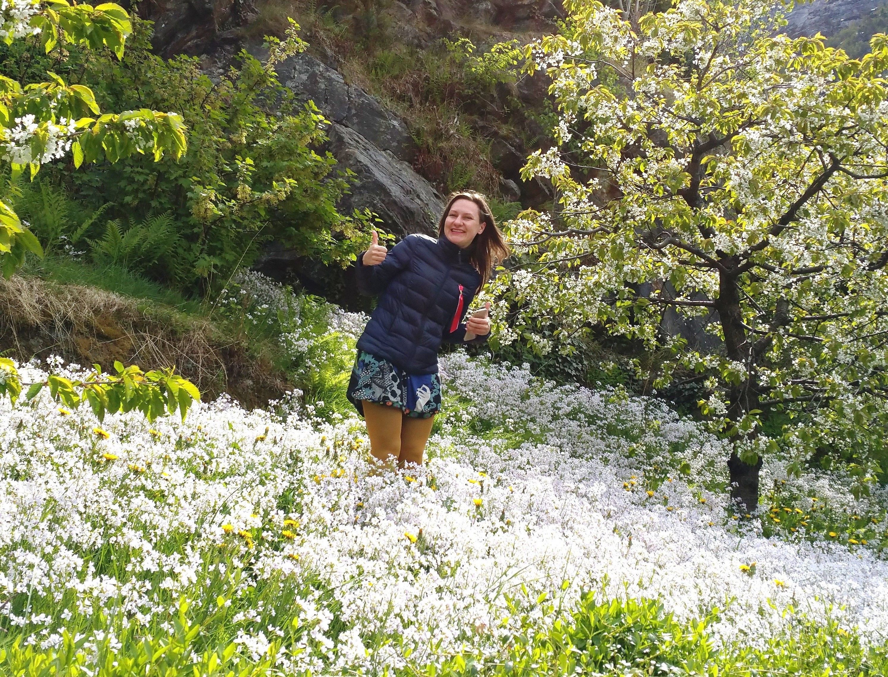 Spring atmosphere at Stana Farm – guest enjoying the blooming orchard with views of the Hardangerfjord.
