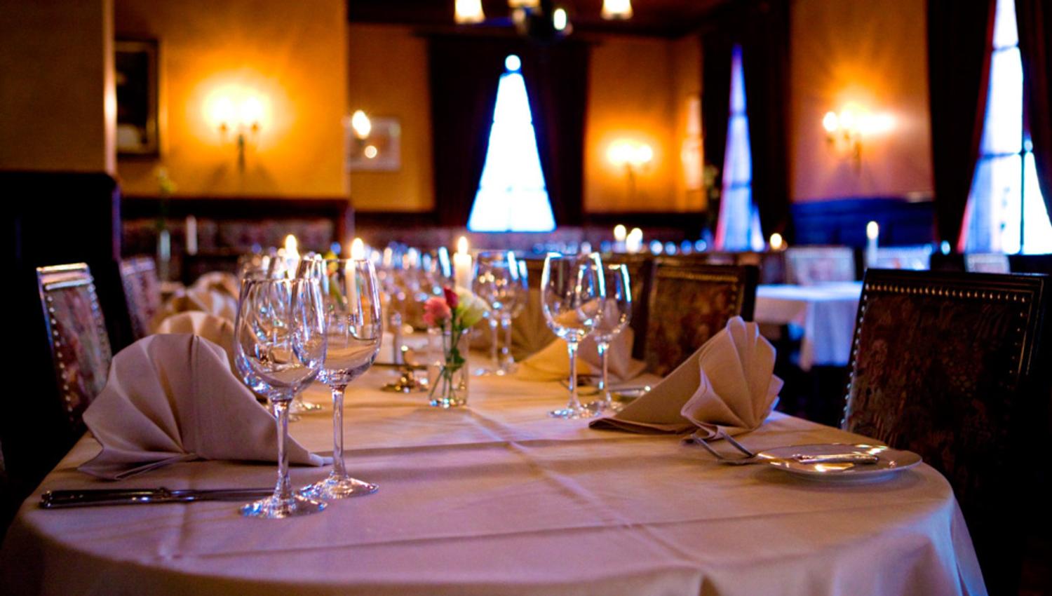 A long table with a white cloth set for dining, with wine glasses.