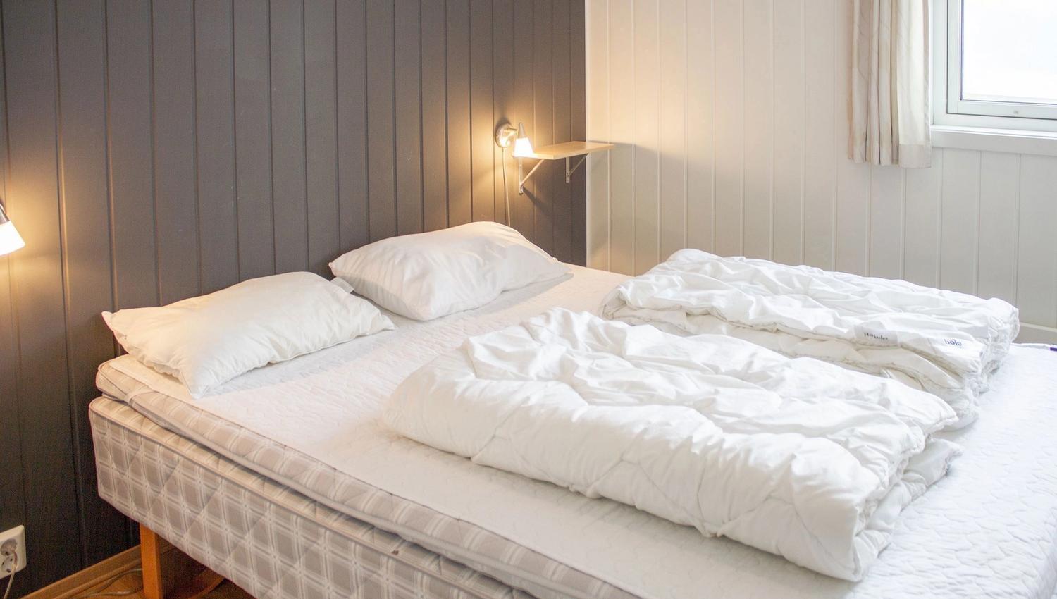A bed with white sheets and pillows.