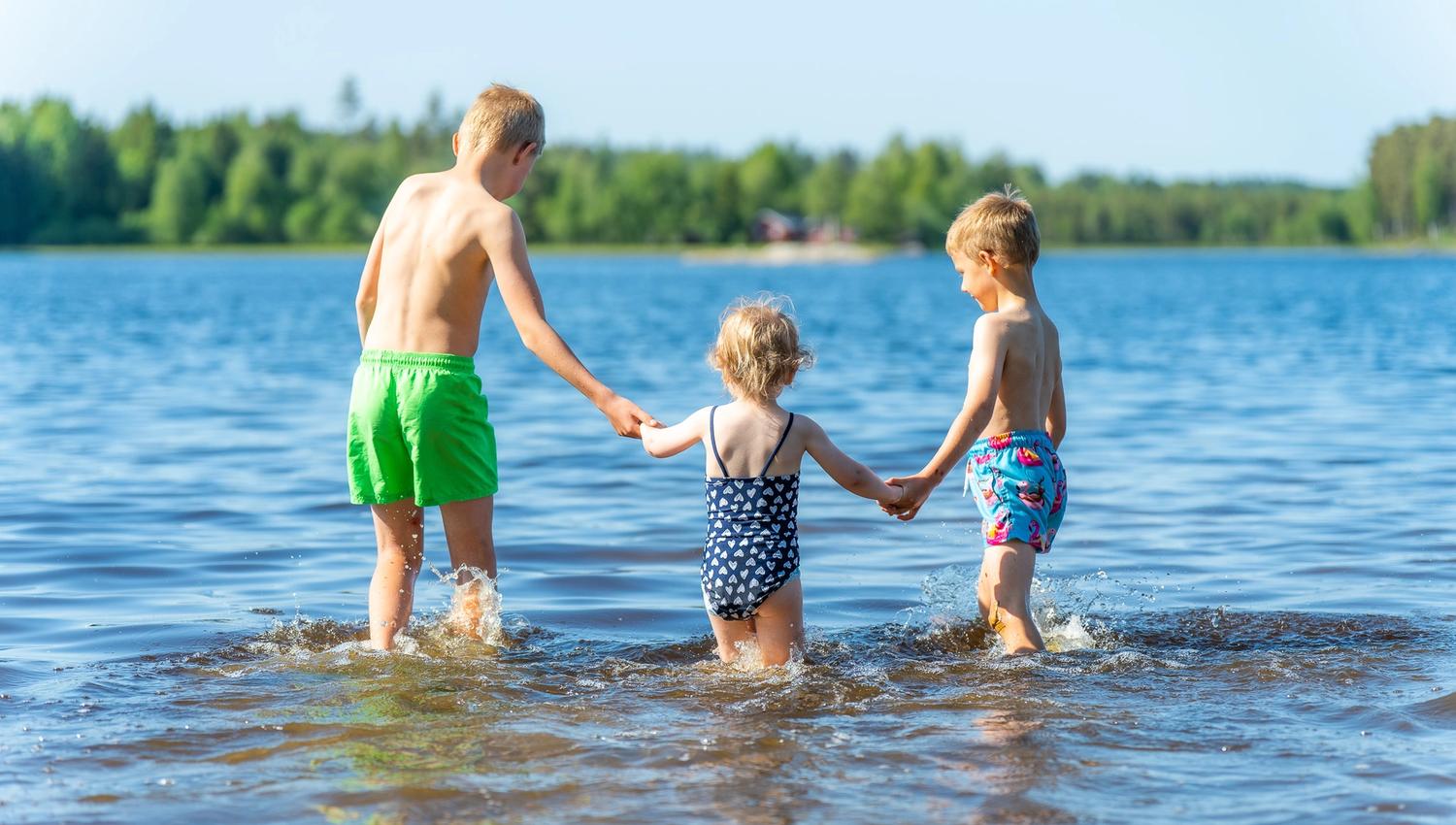Tre barn på vei ut i vannet for å bade