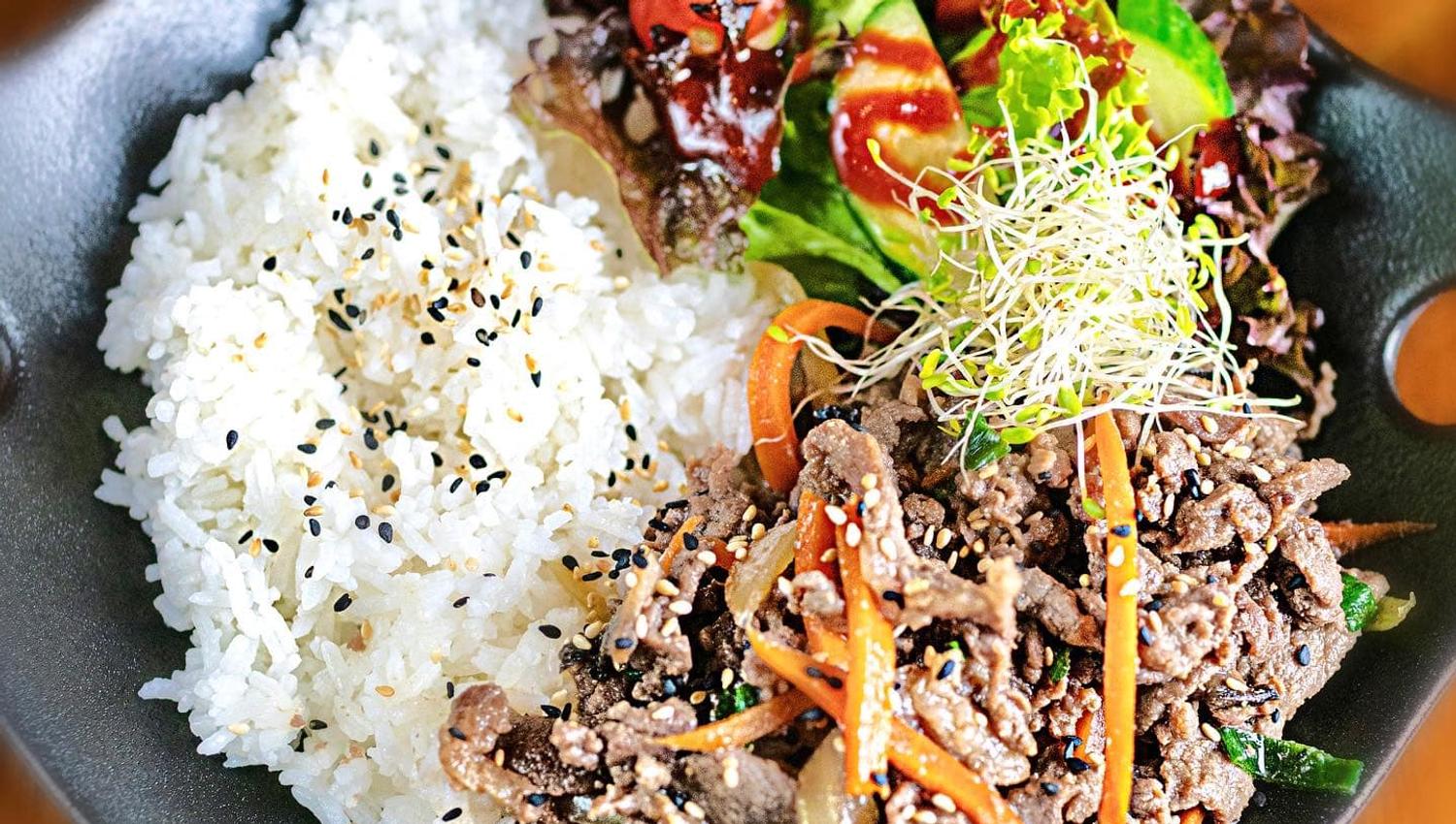 Plate with white rice, meat dish and salad