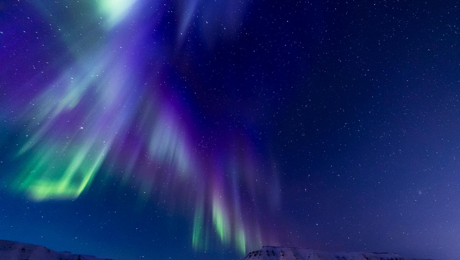 Blue and purple northern lights above the mountains