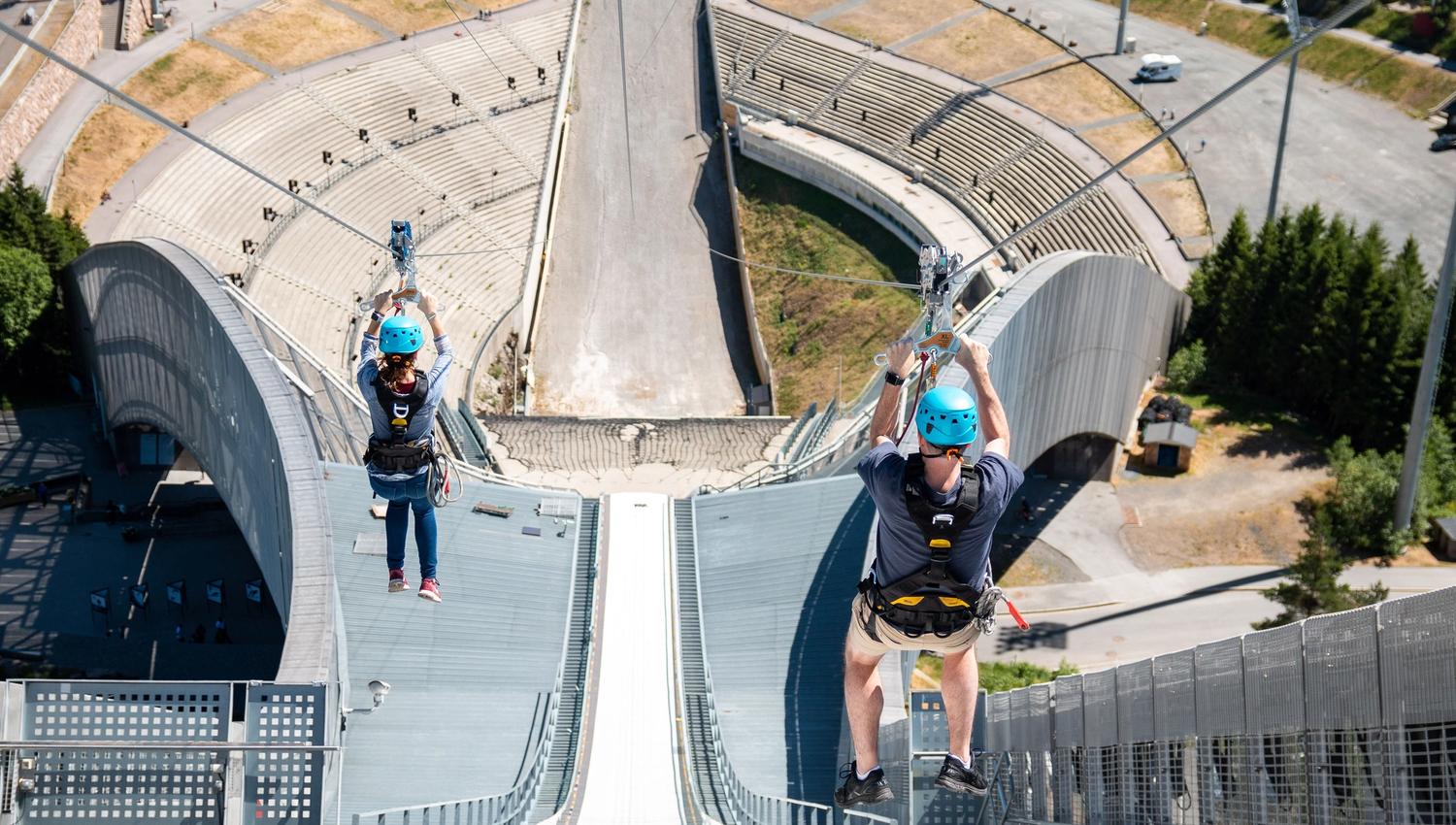 Two people ziplining down Holmenkollen Ski Jump.