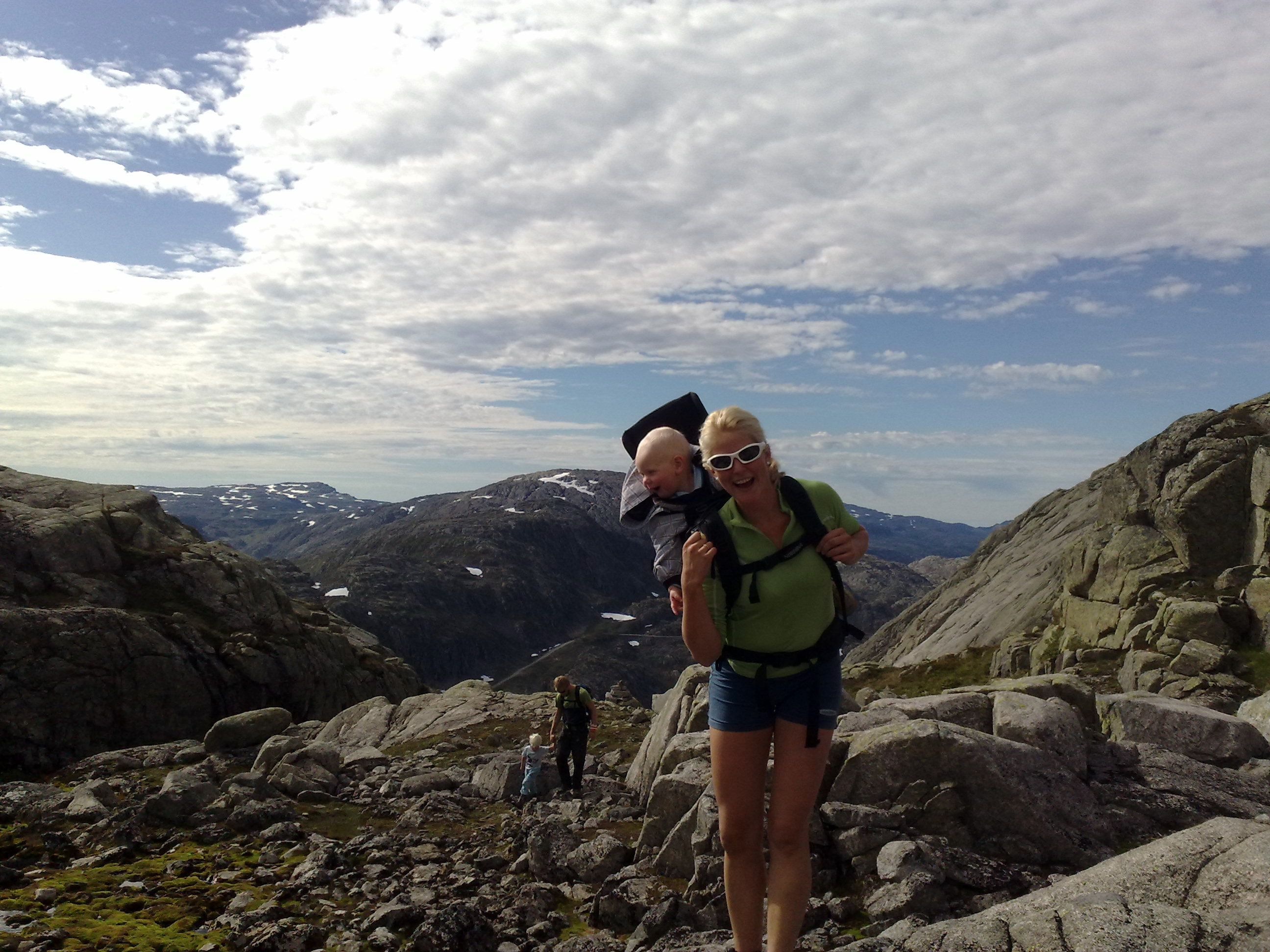 Family hiking to Røldalssåto under clear skies, surrounded by magnificent mountain scenery.
