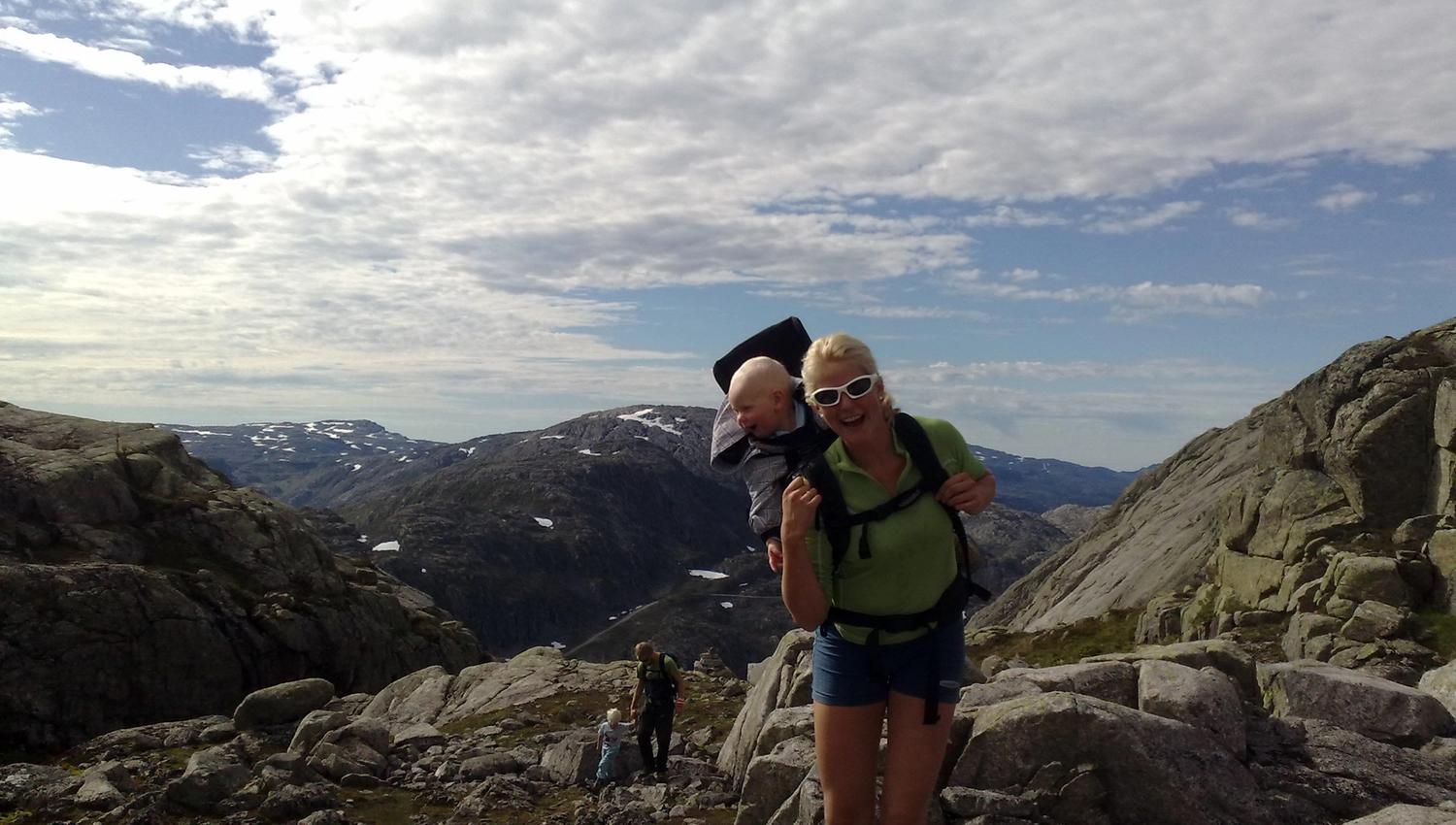 Family hiking to Røldalssåto under clear skies, surrounded by magnificent mountain scenery.