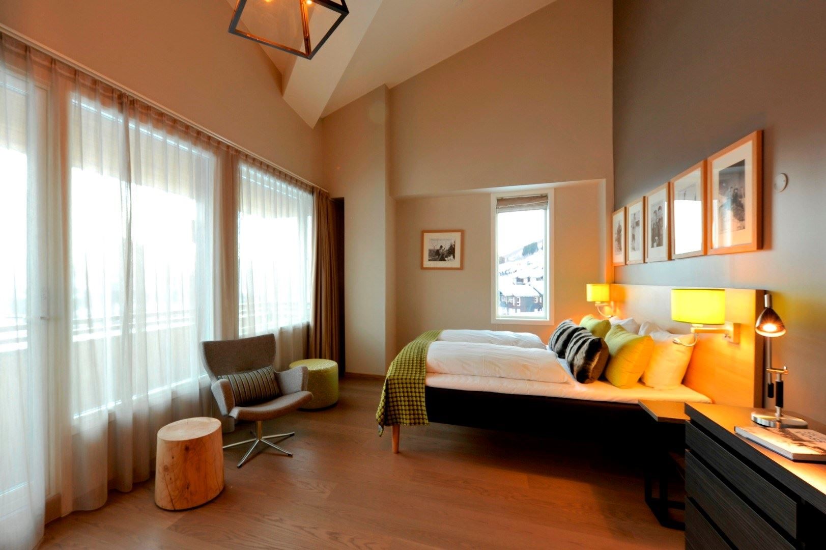 Fint hotellrom med stol, seng og bildar på veggen.