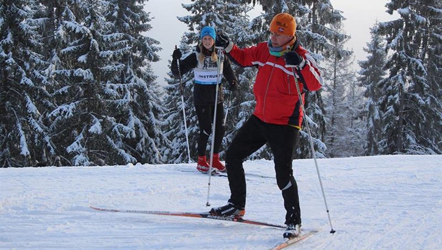 Instructor observing a man skiing