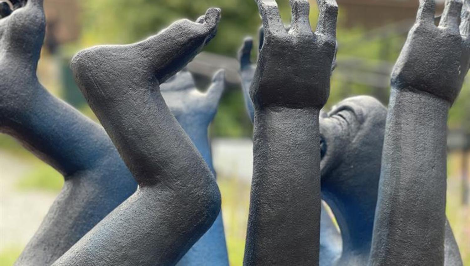 black sculpture - small child lying on its back with lots of arms