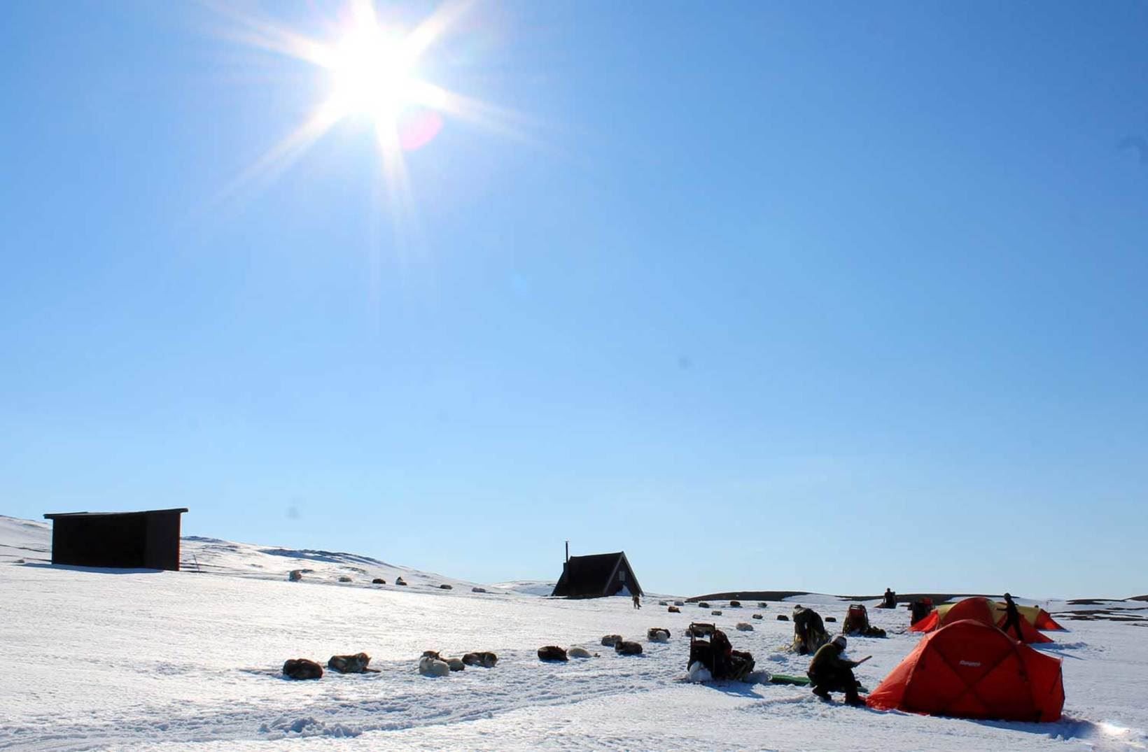 winter landscape, sunshine and tents in the distance