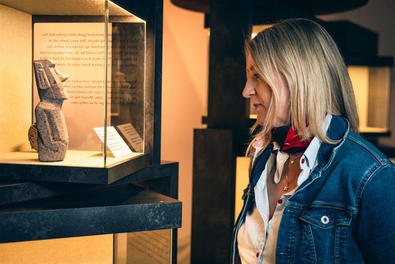 Woman looking at a mini sculpture from Easter Island