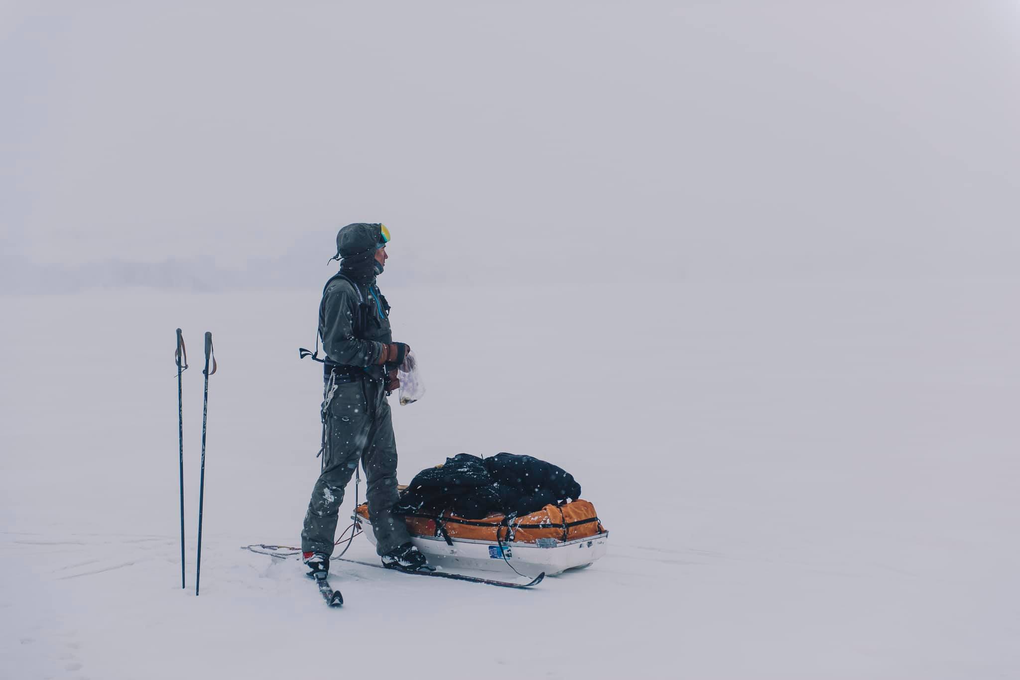 A skier standing next to a sled