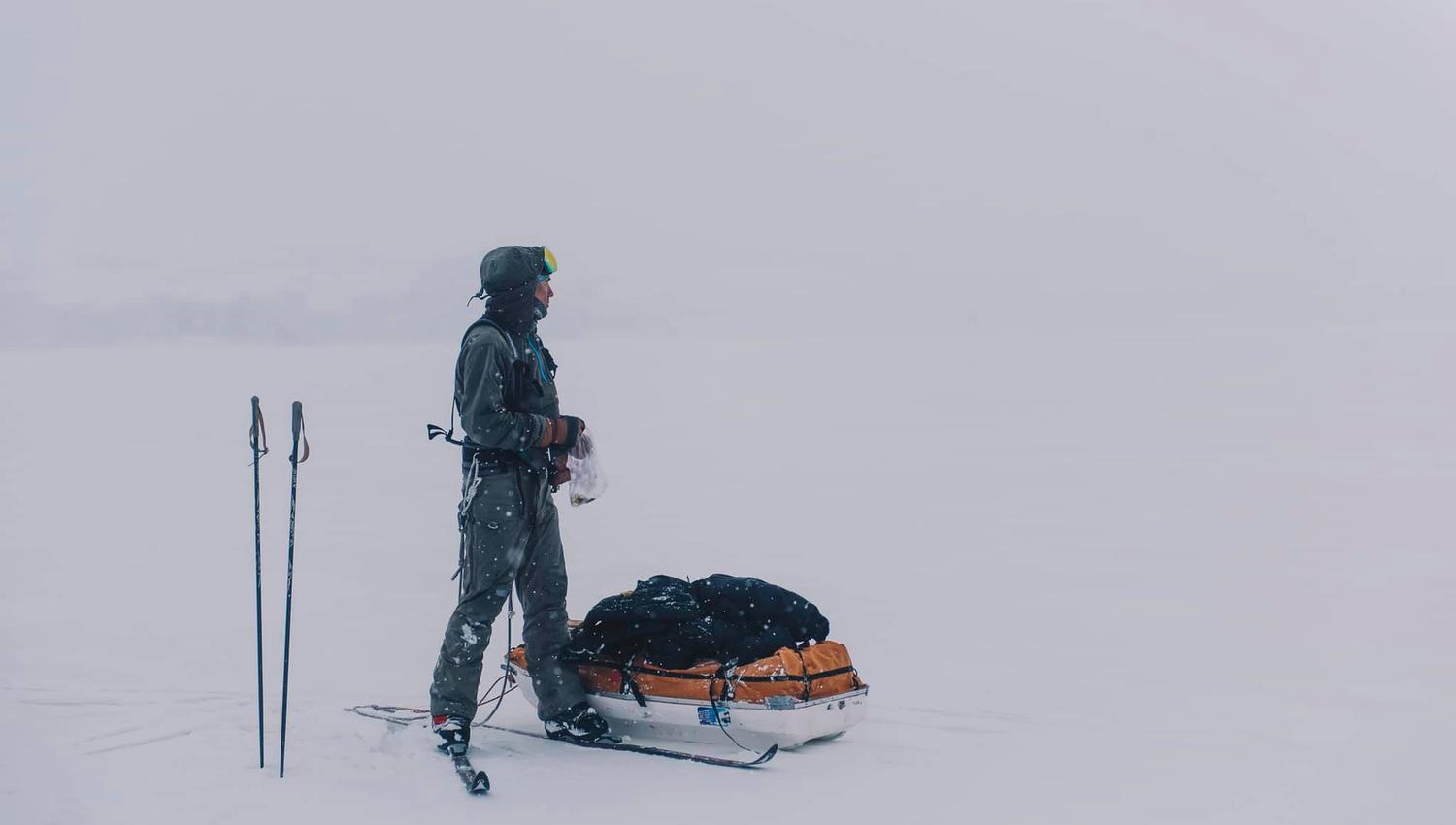 A skier standing next to a sled
