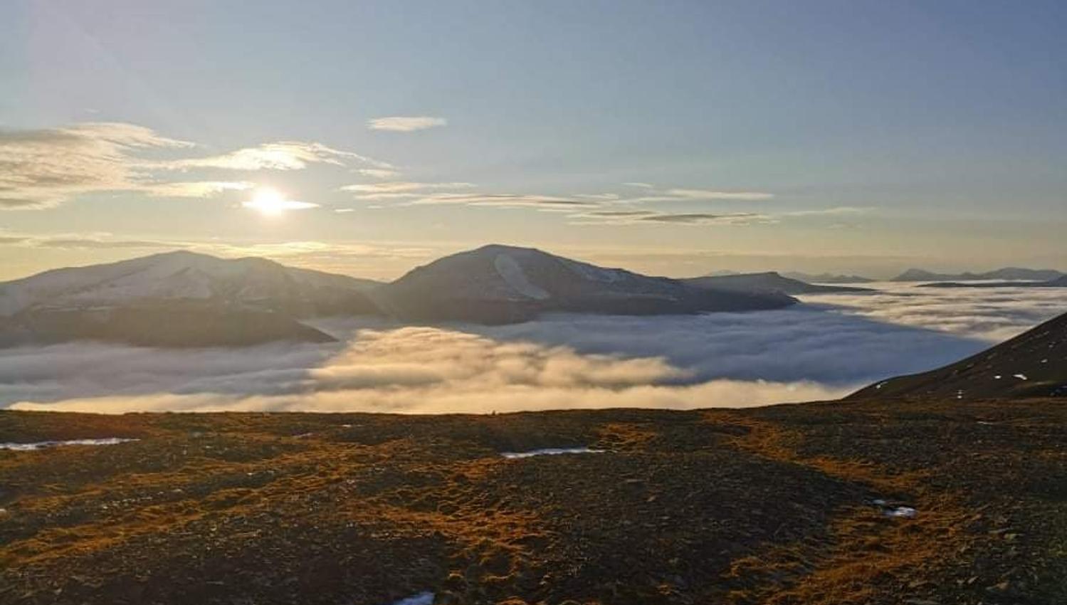 Utsikt fra et fjell med tåke i bunn av dalen