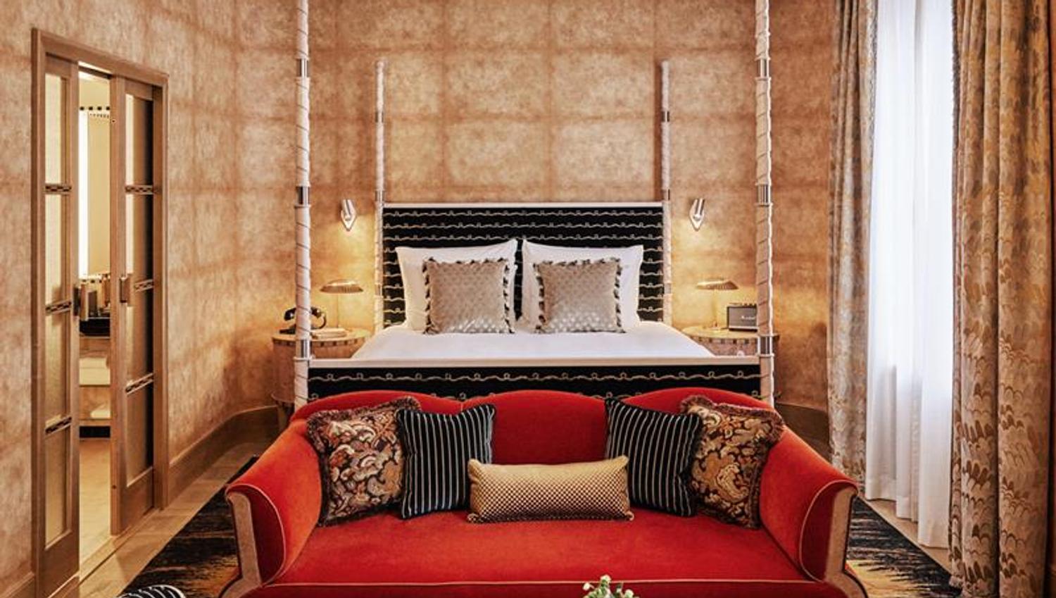 Hotel room with a large double bed behind red sofa