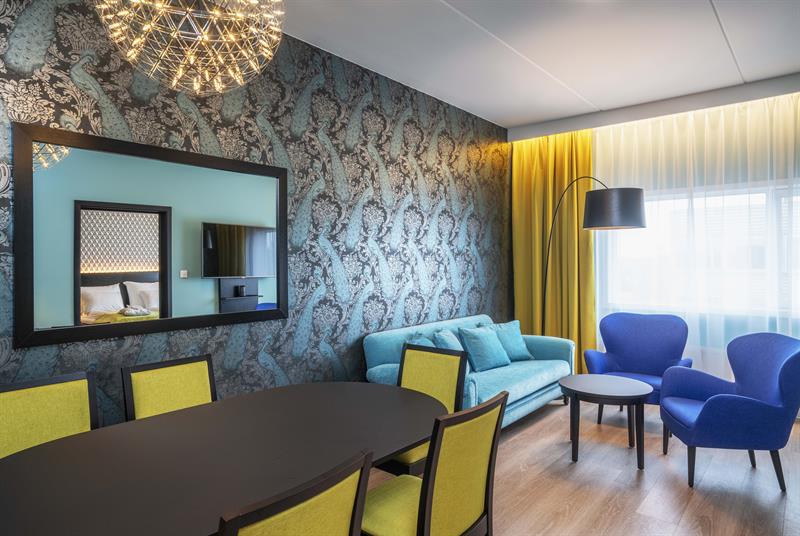 hotell rom med stoler og bord i sterke farger