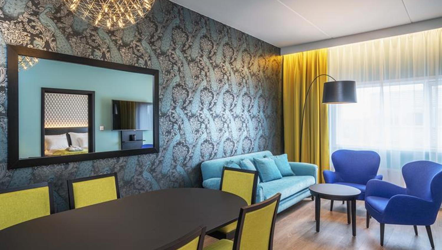 hotell rom med stoler og bord i sterke farger