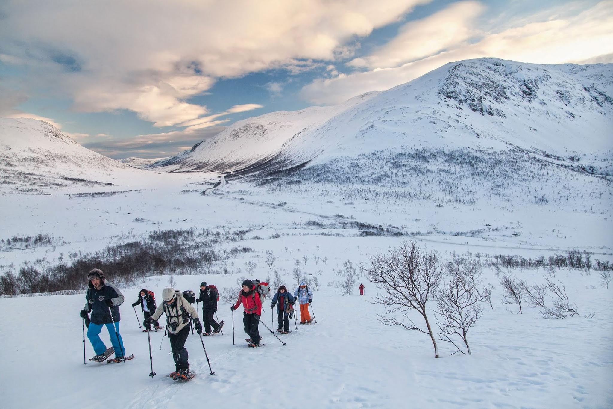 Folk på trugetur i snødekte fjell med vinterutstyr.