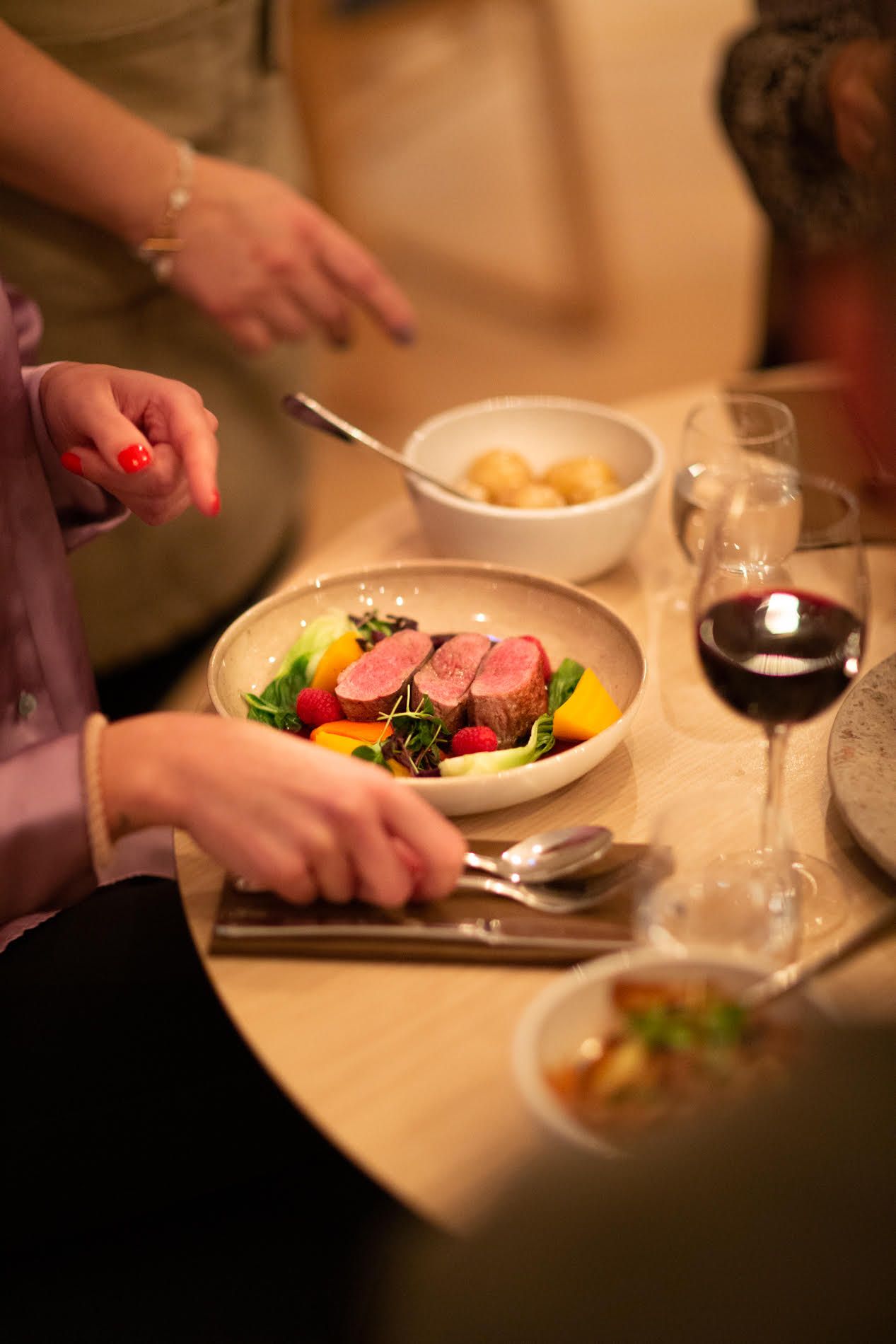 Bord på Lindesnes Havhotell, tallerken med biff, fargerike grønnsaker, poteter og et glass vin