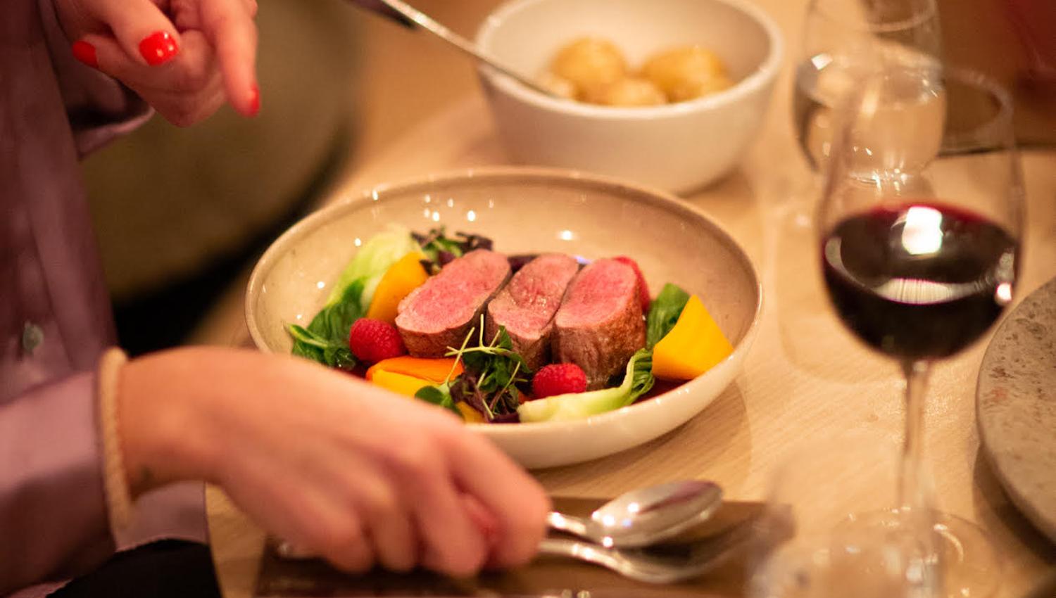 Bord på Lindesnes Havhotell, tallerken med biff, fargerike grønnsaker, poteter og et glass vin