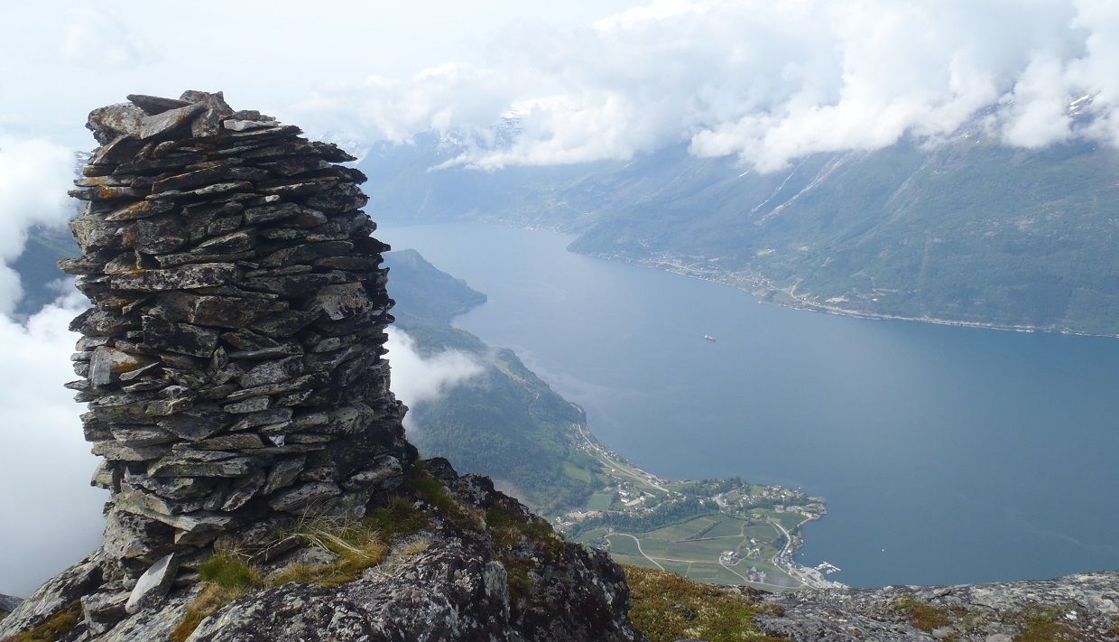 Ein varde på toppen av Dronningstien med utsikt over fjorden og landsbyen Lofthus.