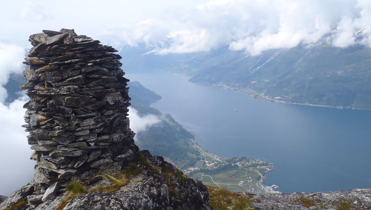 Ein varde på toppen av Dronningstien med utsikt over fjorden og landsbyen Lofthus.