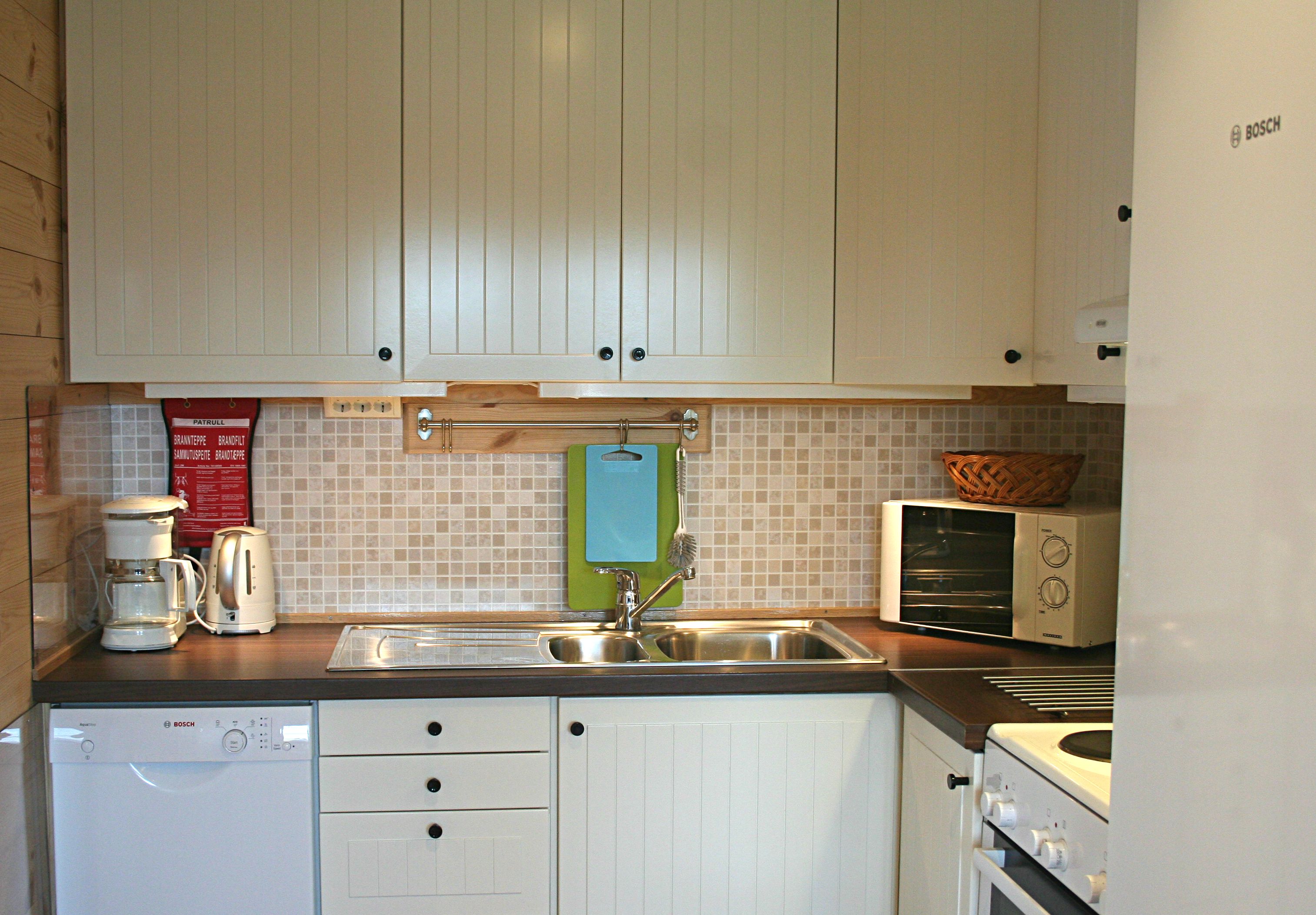 Fully equipped kitchen with white cabinets, stove and dishwasher at Vågen Rom og Hytteutleige in Hardanger.
