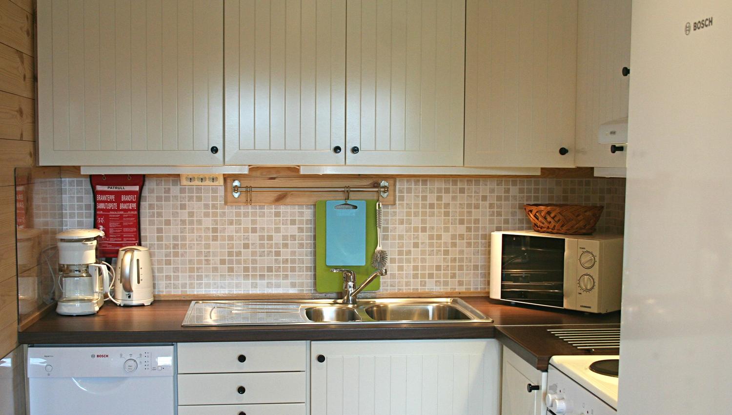 Fully equipped kitchen with white cabinets, stove and dishwasher at Vågen Rom og Hytteutleige in Hardanger.