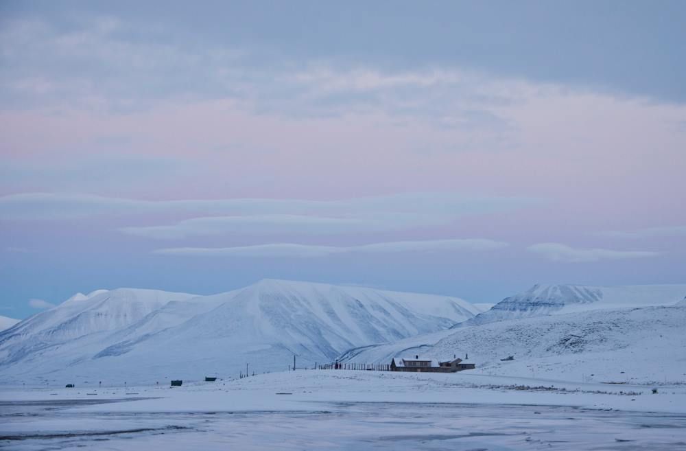 Tommy's Lodge in a snowy landscape with mountains and a pink sky in the background