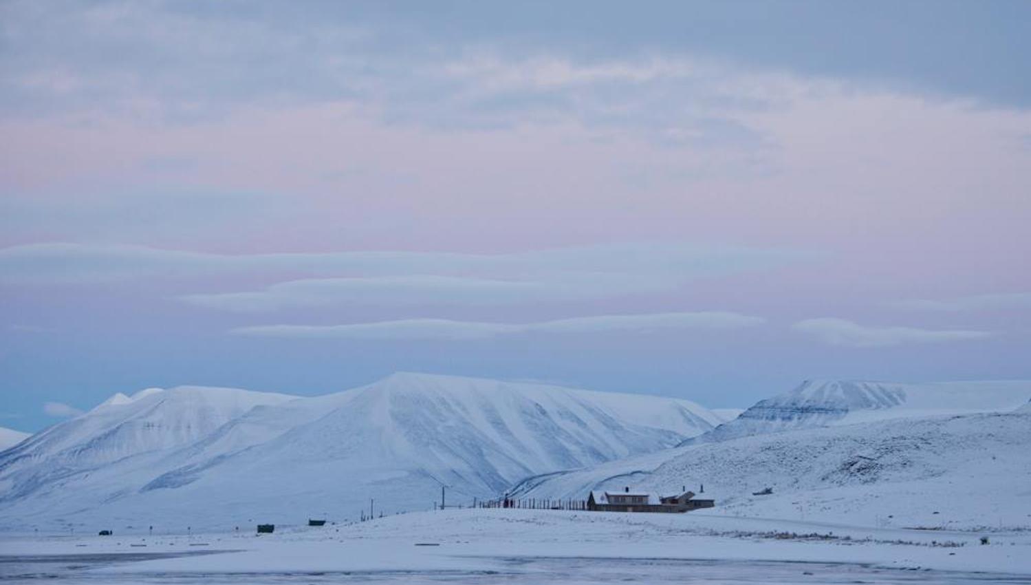 Tommy's Lodge in a snowy landscape with mountains and a pink sky in the background