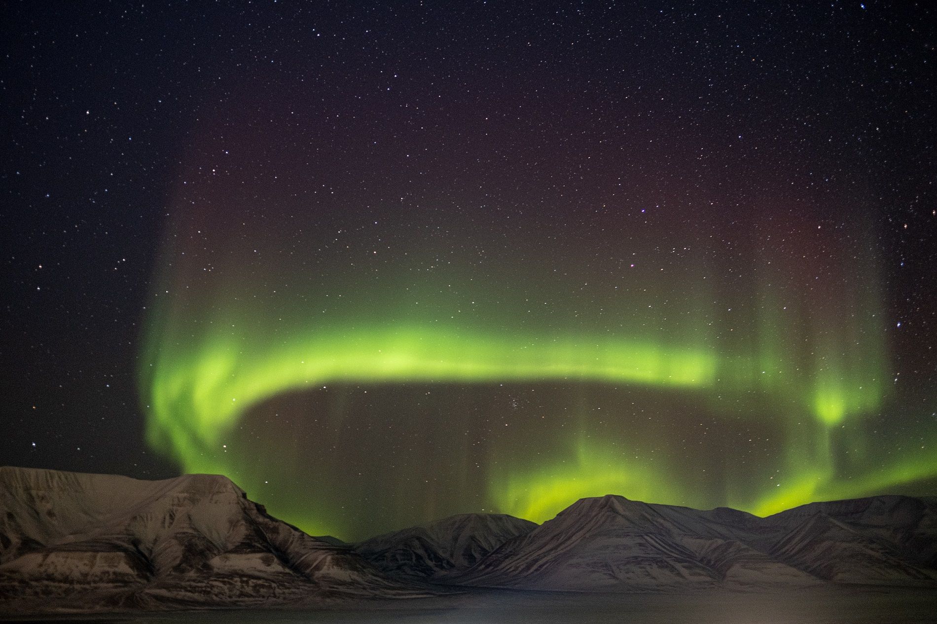 A circle of northern lights in the skies above a mountain range