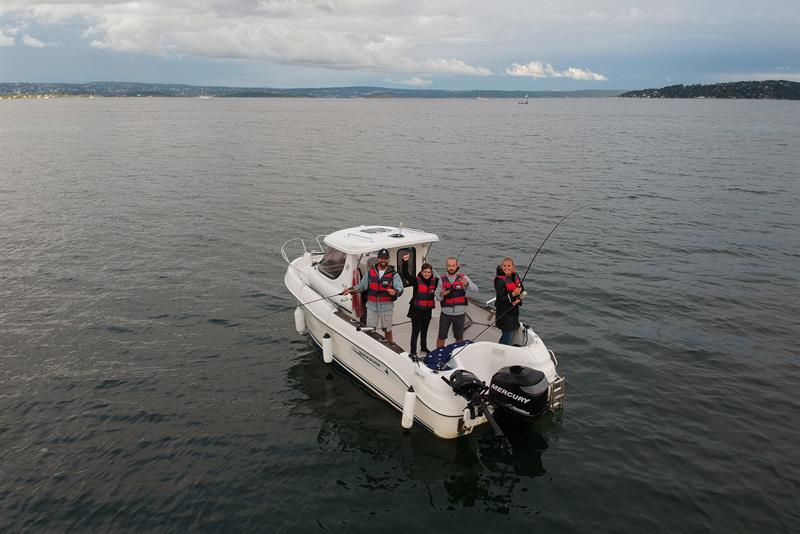 people with a fishing rod on a boat in the fjord