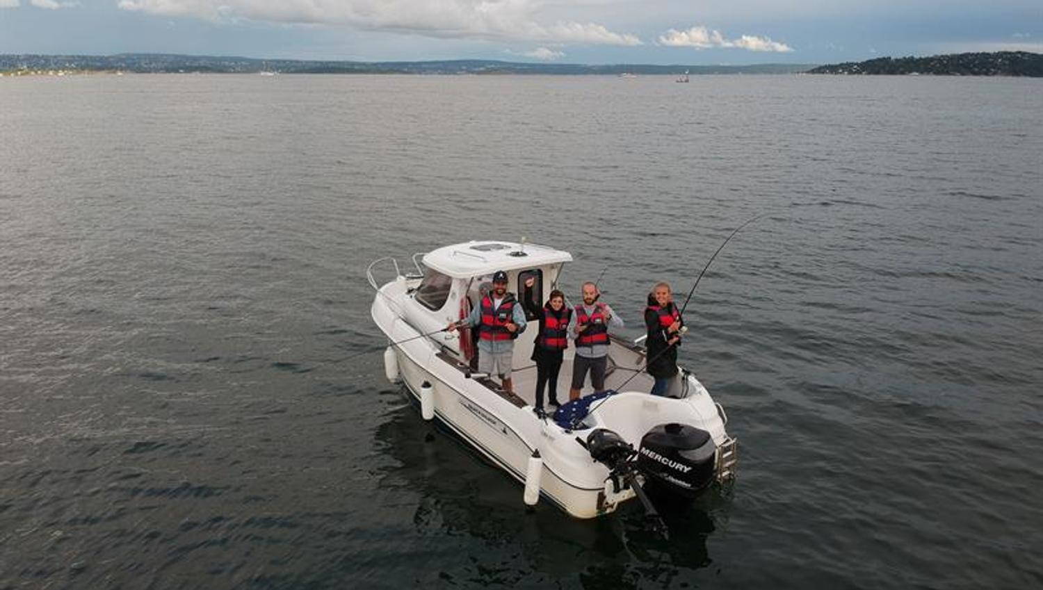 people with a fishing rod on a boat in the fjord