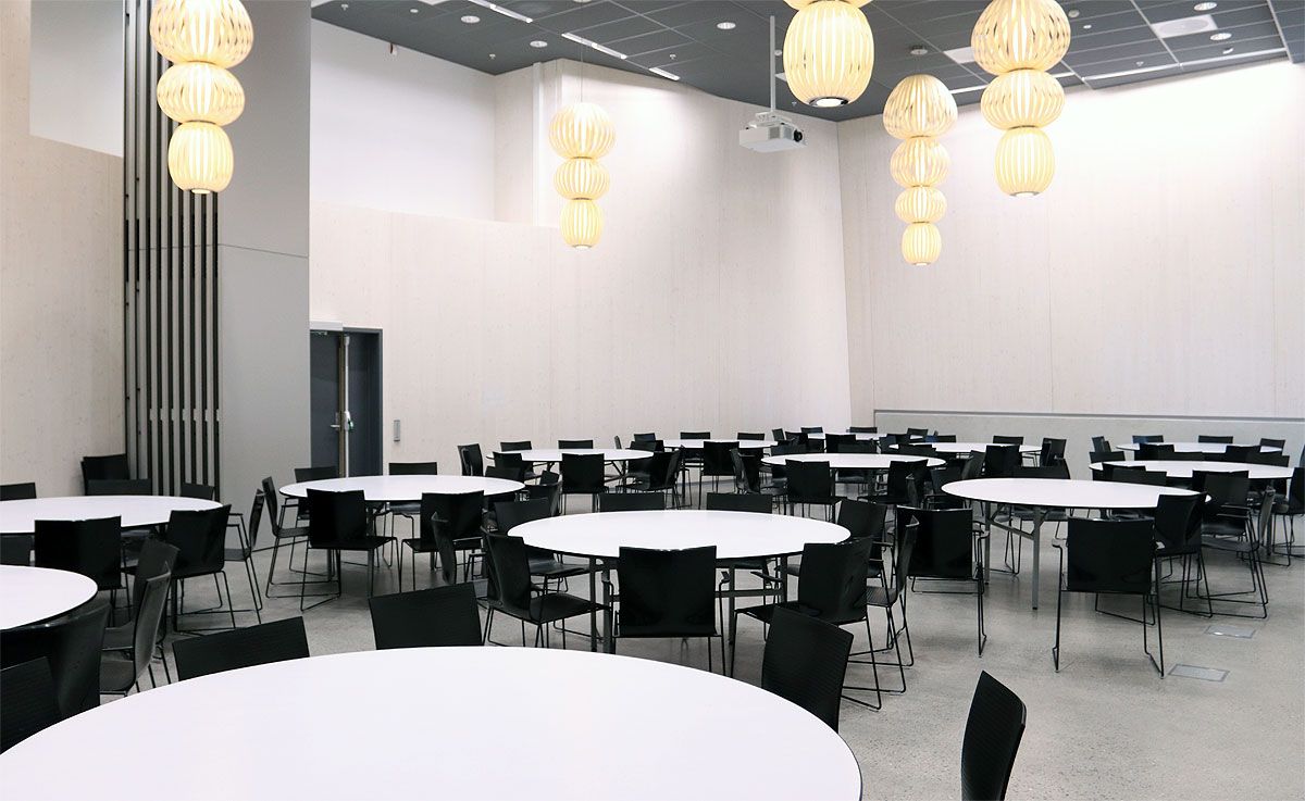 Banquet hall with large, round, white tables and black chairs