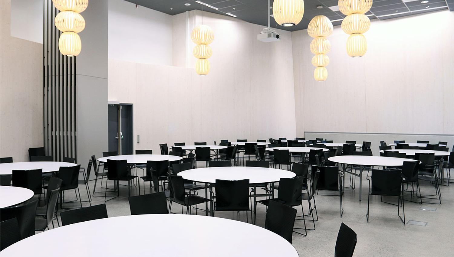 Banquet hall with large, round, white tables and black chairs