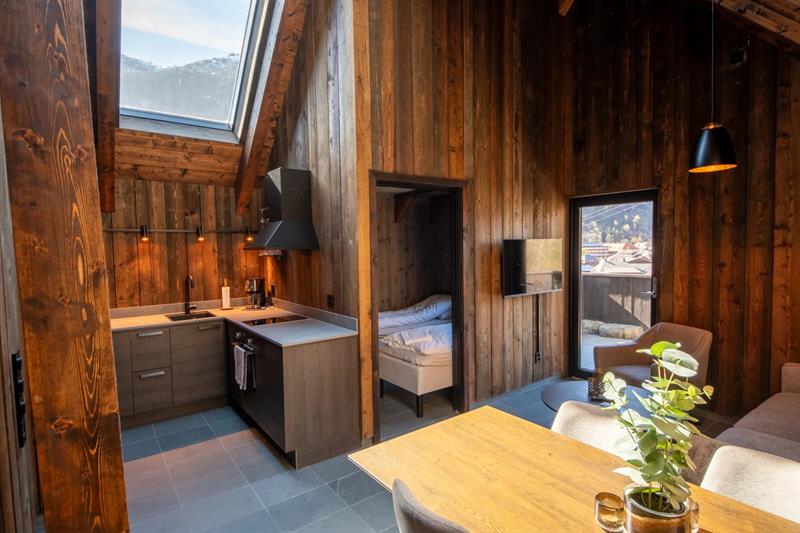 Kjøken og opphaldsrom i vikinghytte på Lothepus Camping med takvindu mot Hardangerfjella