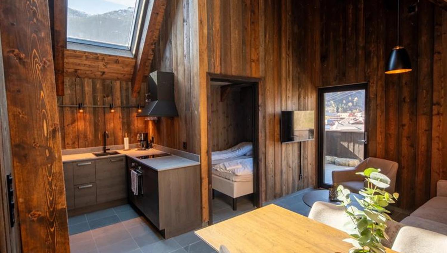 Kjøken og opphaldsrom i vikinghytte på Lothepus Camping med takvindu mot Hardangerfjella