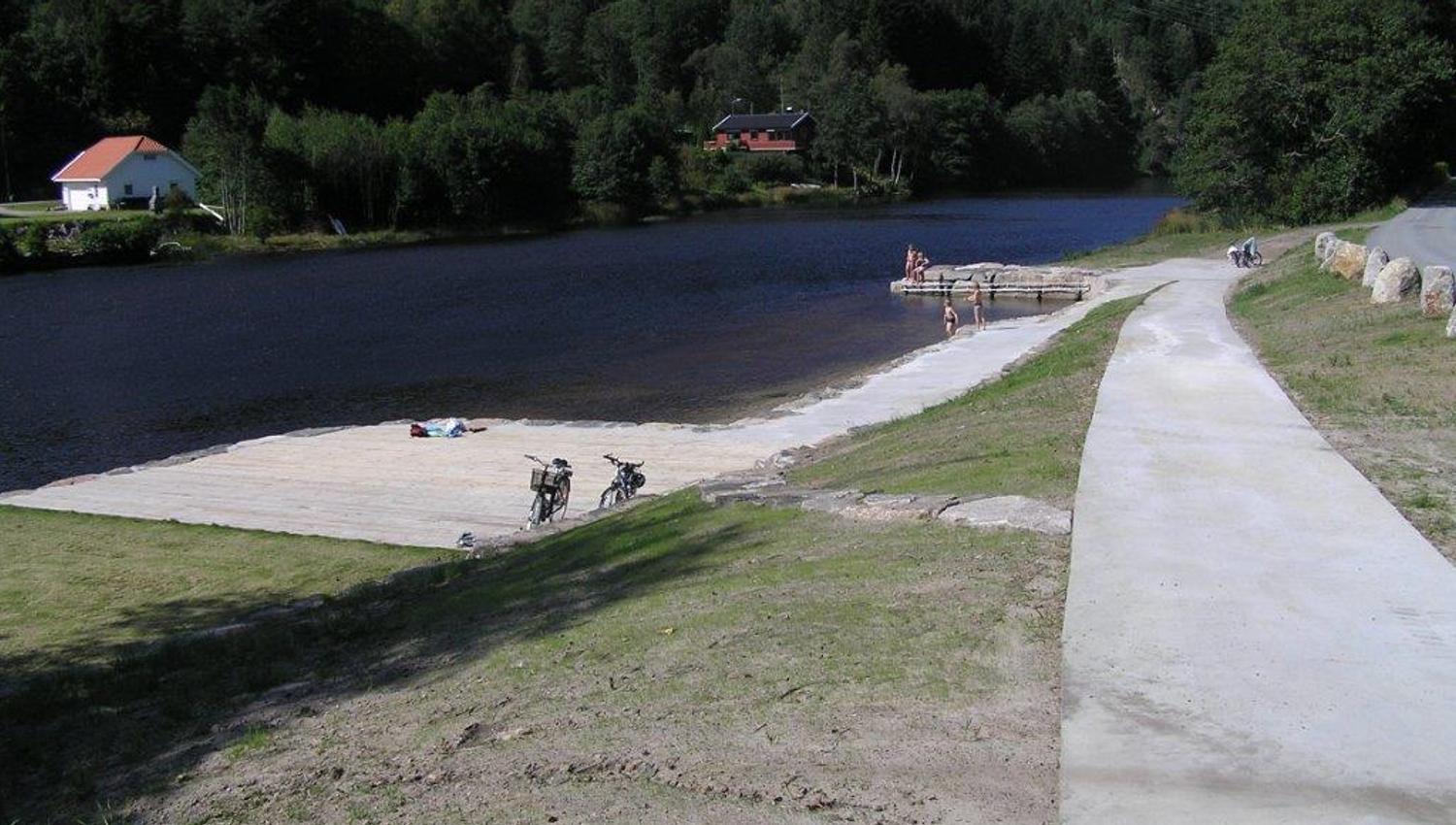 Vallemoen badeplass, treplatting med sykler plassert pent langs kanten. Flere mennesker som er på brygga