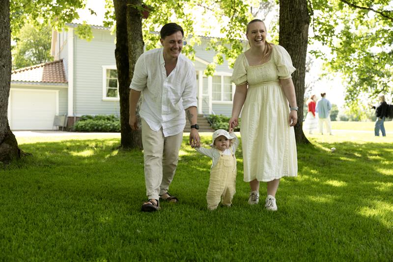 a family with a small child walking along a tree-lined path in a historic park setting.