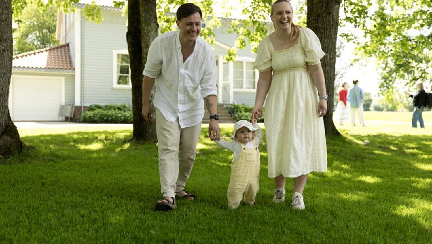 a family with a small child walking along a tree-lined path in a historic park setting.