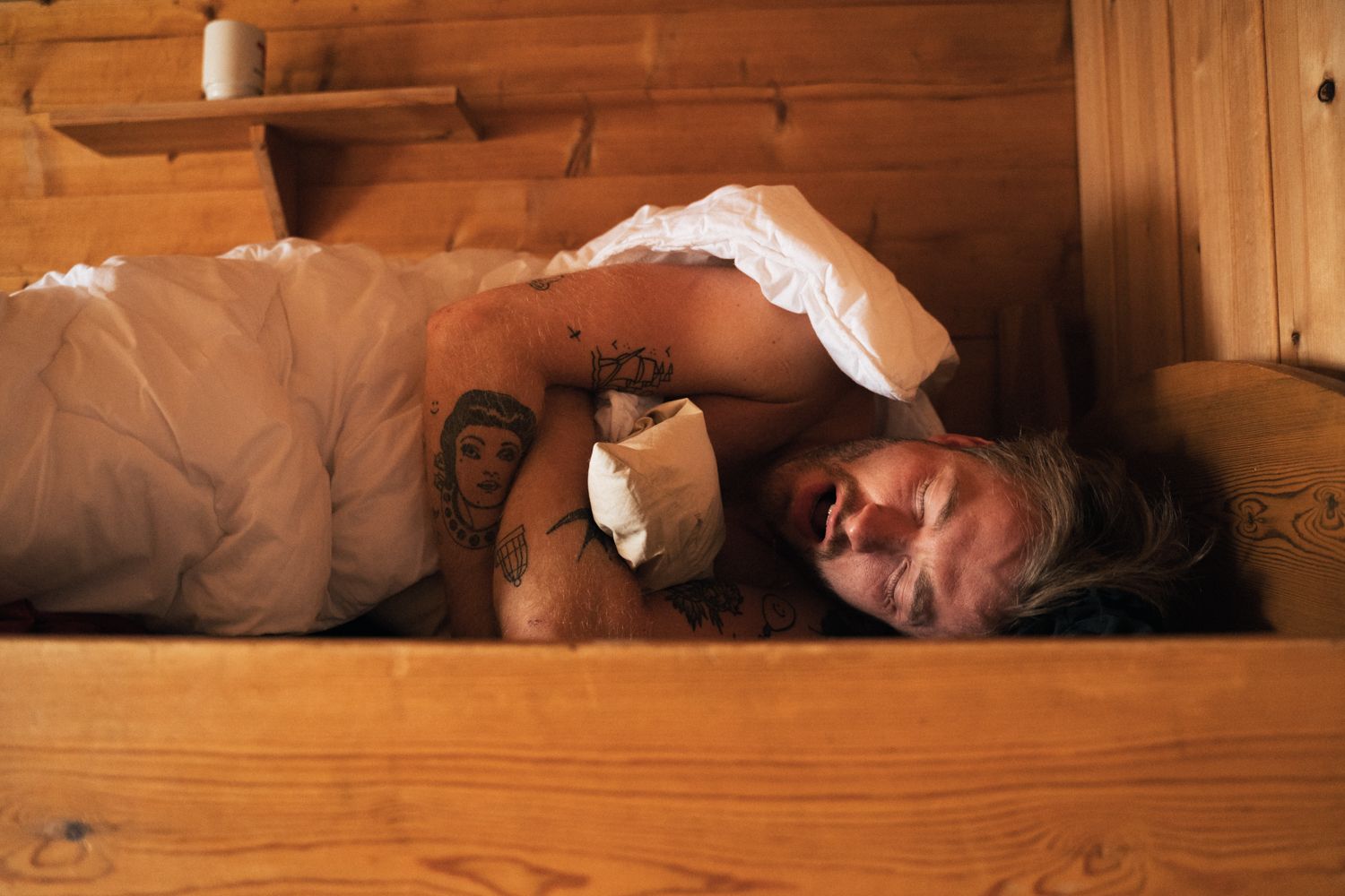 A man yawning in a bed.