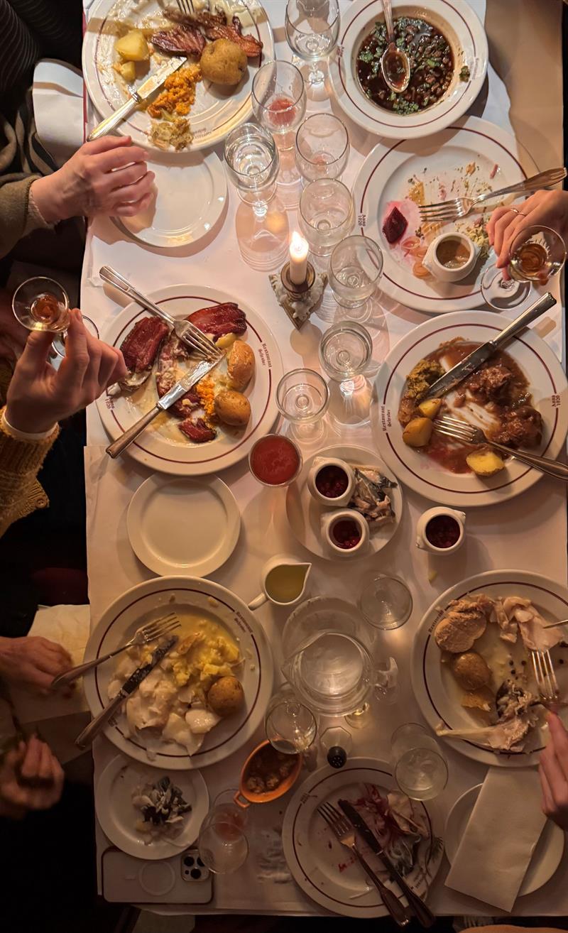 Long table filled with traditional Norwegian dishes, candlelight and guests sharing a meal at Restaurant Schrøder.