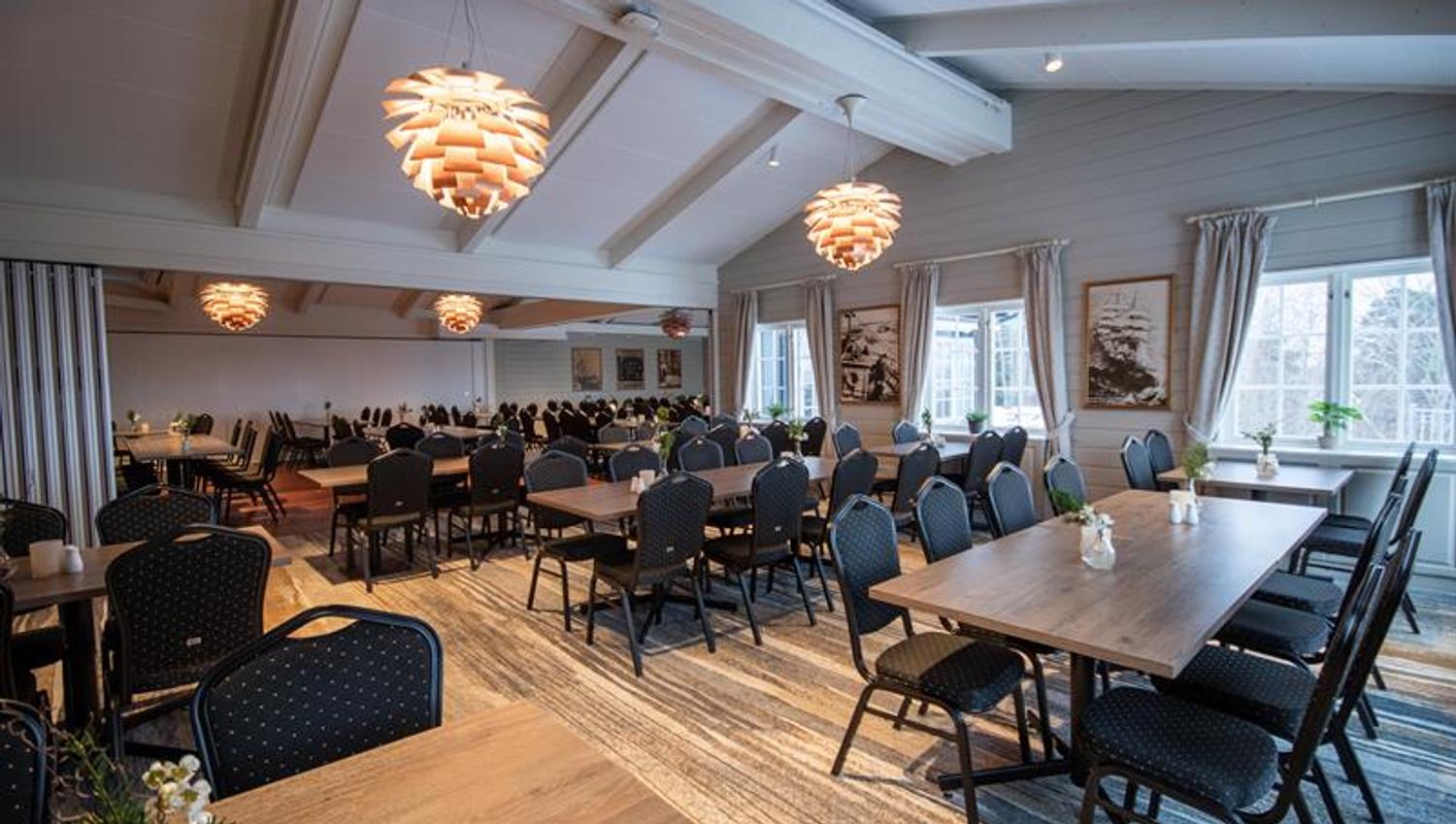 Restaurant with many chairs and tables. Light painted walls and tilted ceilings.